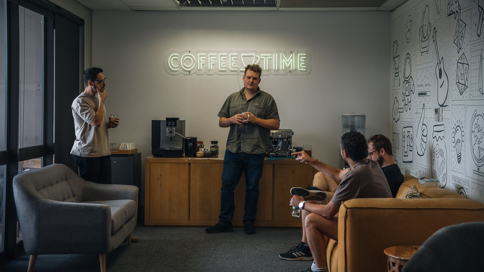 The team chatting over coffee under the Coffee Time sign